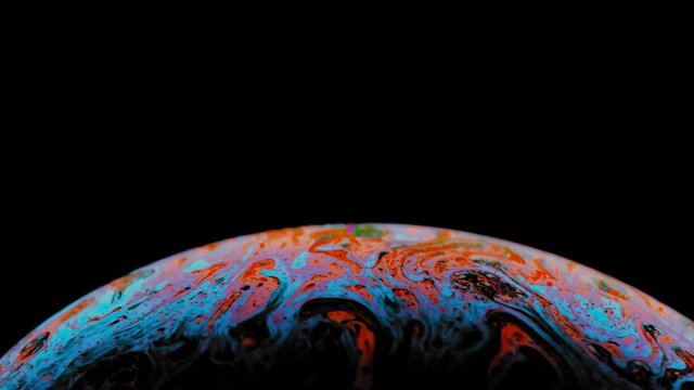Macro shot of a soap bubble creates a colorful and black background