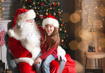 Fototapeta na wymiar Santa Claus and little girl in room decorated for Christmas