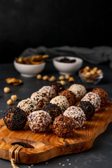 Energy balls of nuts, oatmeals and dried fruit in plate on dark background, vertical orientation