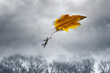 Man flying with a big leaf. Man flies on the last autumn leaf to the sky. Maple leaf folded like a paper plane in storm sky. Freedom concept. Concept of bygone time