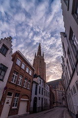 Street of Bruges and Church of Our Lady with beautiful cloudy sunrise. Bruges, Belgium