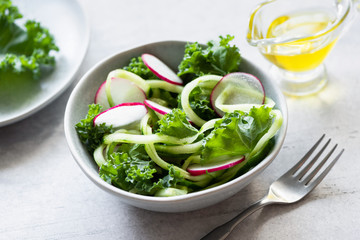 Vegan green salad with kale, cucumber and radish dressed with extra virgin olive oil