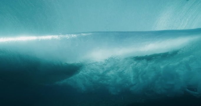 Underwater shot looking out from the back of a barreling wave toward island mountains, amazing clear underwater ocean wave barrel
