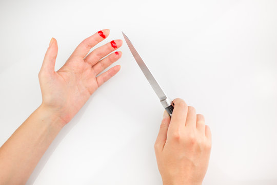 Acciden with kitchen knife. child fingers of left hand with bleeding open cut and right hand holding knife on a white background