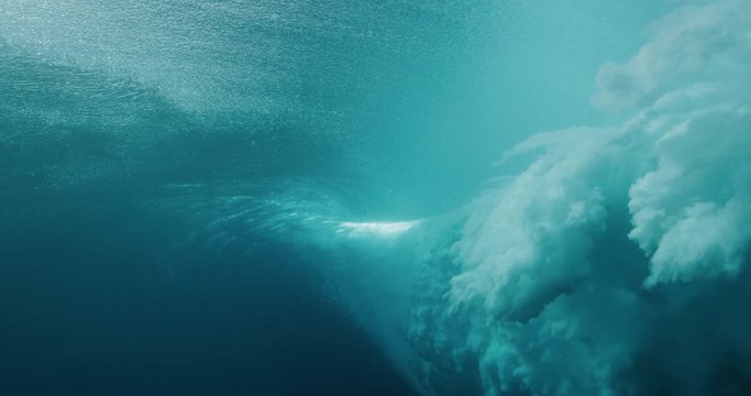 Underwater shot of blue ocean wave breaking over the camera with turbulence clouds