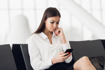 Woman Reading Phone Messages in Airport Waiting Room. Happy girl buying e-ticket, making hotel reservations and checking in online.