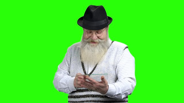 Old bearded man using glass digital tablet. Green Chroma Key background. Modern technologies for retires.