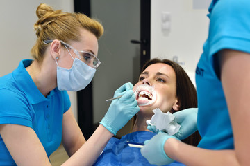 Dentist And Assistant Examine Patient With Braces In Dental Office. Health Care Concept