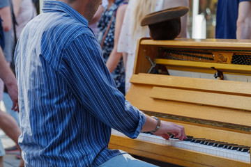 Close-up outdoor view of street artist's hand play the old vintage wooden piano on walking street...