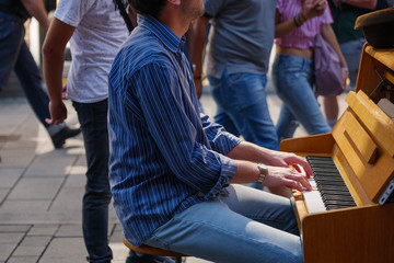 Close-up outdoor view of street artist's hand play the old vintage wooden piano on walking street in Europe. Pianist show street performance on crowdy street.