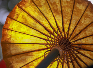 Light shines making an orange glow on the paper of a bamboo umbrella