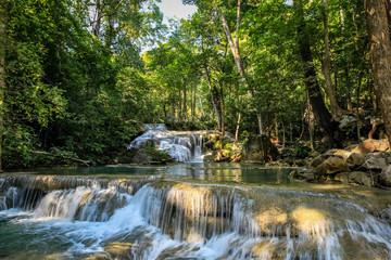 A series of beautiful short waterfalls and flat pools in the dense forest of Erawan National park in Thailand