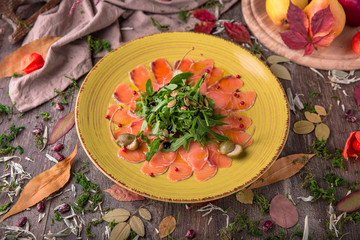 Beef and salmon carpaccio with arugula and pine nuts. Snack.