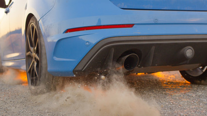 CLOSE UP Car starts and quickly drives away, tires spinning, raising sand & dust © helivideo