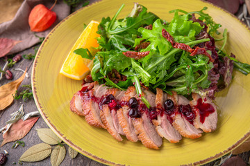 Sliced duck fillet in berry sauce with green salad with pine nuts