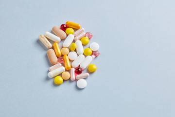 Multicolor vitamins and supplements on bright paper background. Concept for a healthy dietary supplementation. Top view. Copy space. 