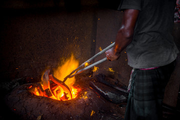 Fototapeta premium Unsafe worker hands. A local steel machine parts making yard worker melting scrap on hot furnace.