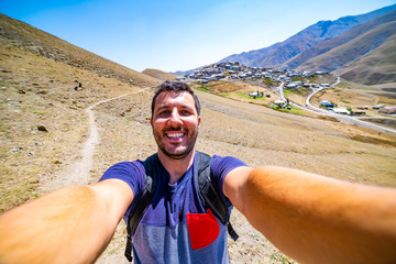 happy man backpacker take selfie photo in Khinalug which is an ancient Caucasian village located in the mountains of Quba Region, Azerbaijan. 