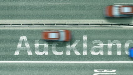 Aerial top down view of the road with cars revealing Auckland caption. Car travel in New zealand conceptual clip