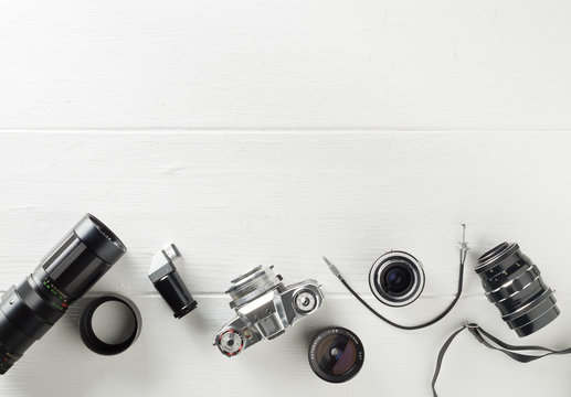 Retro analog film camera with lenses and photography equipment on white wooden background with copy space - photography or creativity concept, flat lay top view from above