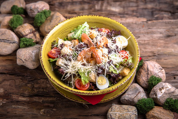 Nutritious, vitamin, healthy salad Classic Caesar with grilled shrimps, cheese, herbs, crackers, sauce.  Rustic Still Life