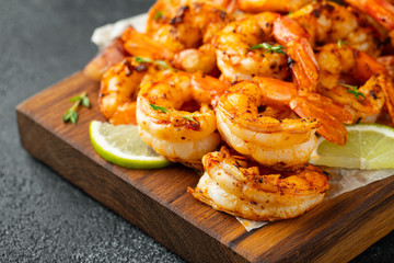 Grilled shrimps or prawns served with lime, garlic and white sauce on a dark concrete background....