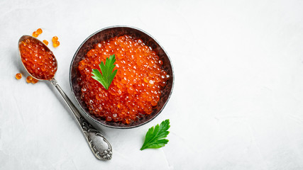 Delicious red caviar in black bowl on a light concrete background. Top view with copy space. Flat lay