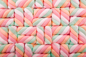 Top view on background texture of colorful twisted marshmallow candies. Copy space for your text. - obrazy, fototapety, plakaty