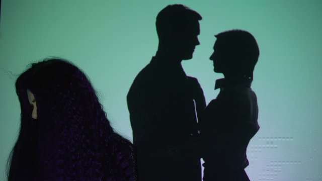Crying girl turning head from silhouette couple kissing on background, betrayal