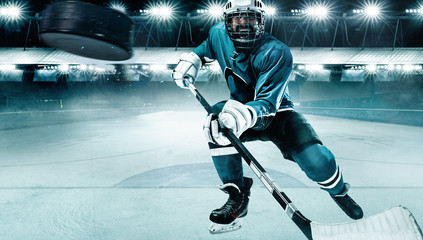 Naklejka premium Ice Hockey player athlete in the helmet and gloves on stadium with stick. Action shot. Sport concept.