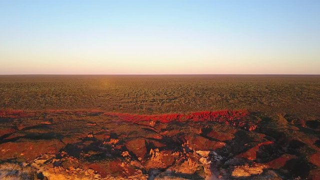 Scenic panoramic aerial drone view at sunset of flight high above ocean and remote beach in Western Australia, with rocky cliff coastline, summer sunny blue sky and horizon as background and copy spac