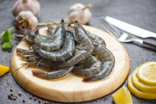 raw shrimps on wooden cutting board plate fresh shrimp prawns for cooking with spices lemon and celery garlic on dark background in the seafood restaurant