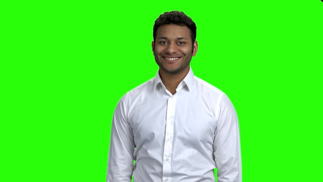Handsome man in white shirt on green screen. Portrait of friendly Indian guy looking at camera. Chroma Key background.