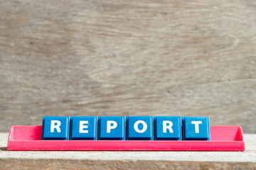 Tile letter on red rack in word report on wood background
