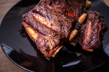 Roasted beef barbecue ribs in grills black dish on wooden table