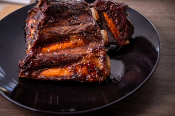 Roasted beef barbecue ribs in grills black dish on wooden table