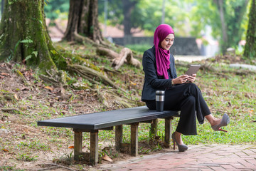 Fototapeta premium Muslim Businesswon on her table during a coffee break. Outdoor setting at a park.