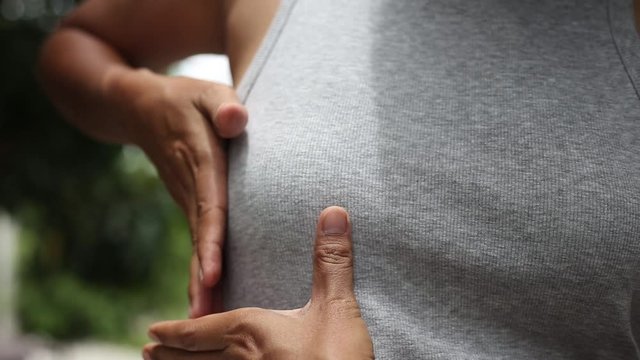 Young woman putting her hand on breast for checking size or cancer awareness , health care concept