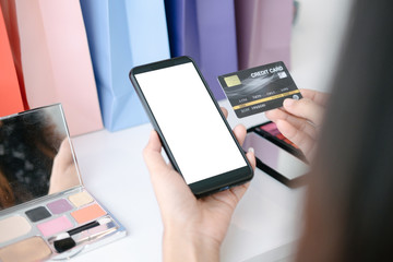Mockup image of Beautiful woman holding credit card shopping online with smartphone on online websites, mockup concept