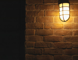 Beautiful vintage orange lamp with light hang on dark brown brick wall with copy space.