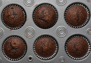 HIgh angle shot of a muffin pan with 6 fresh baked chocokate muffins
