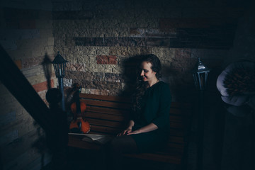 beautiful girl in a green dress reading a book. Art: the book, the violin, the lights. The concept of advertising musical instruments, fashion, symbols, art