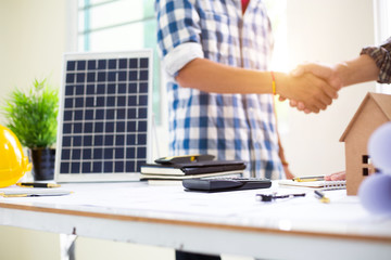 Team Engineers are shaking hand  solar panel Business for home construction designs to bring them to prospective customers.concept