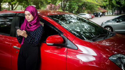 Muslim Female with her smartphone beside her car. Car insurance concept. © hafizismail