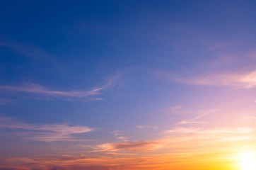 Naklejka na ściany i meble Bright sunset on a blue sky with bright sun and clouds.