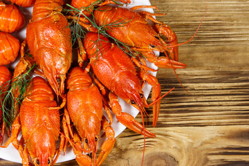 Boiled crayfish in plate on wooden table. Top view