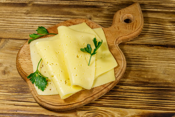Slices of cheese on cutting board on wooden table