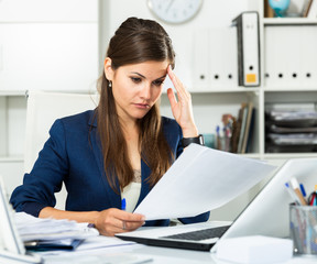 Tired young businesswoman working with documents in office