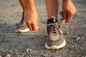 Female hands tying shoelace on running shoes before practice. Runner getting ready for training. Sport active lifestyle concept. Close-up. 