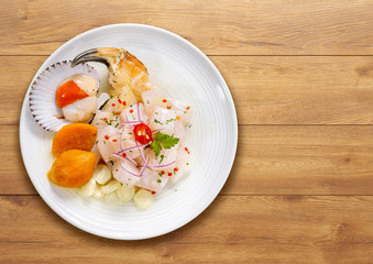 Cebiche de pescado tradicional peruano, vajilla blanca sobre fondo de madera, 